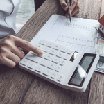 Person calculating how much does a criminal defense attorney cost with calculator, cash, and legal documents on desk