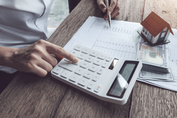 Person calculating how much does a criminal defense attorney cost with calculator, cash, and legal documents on desk