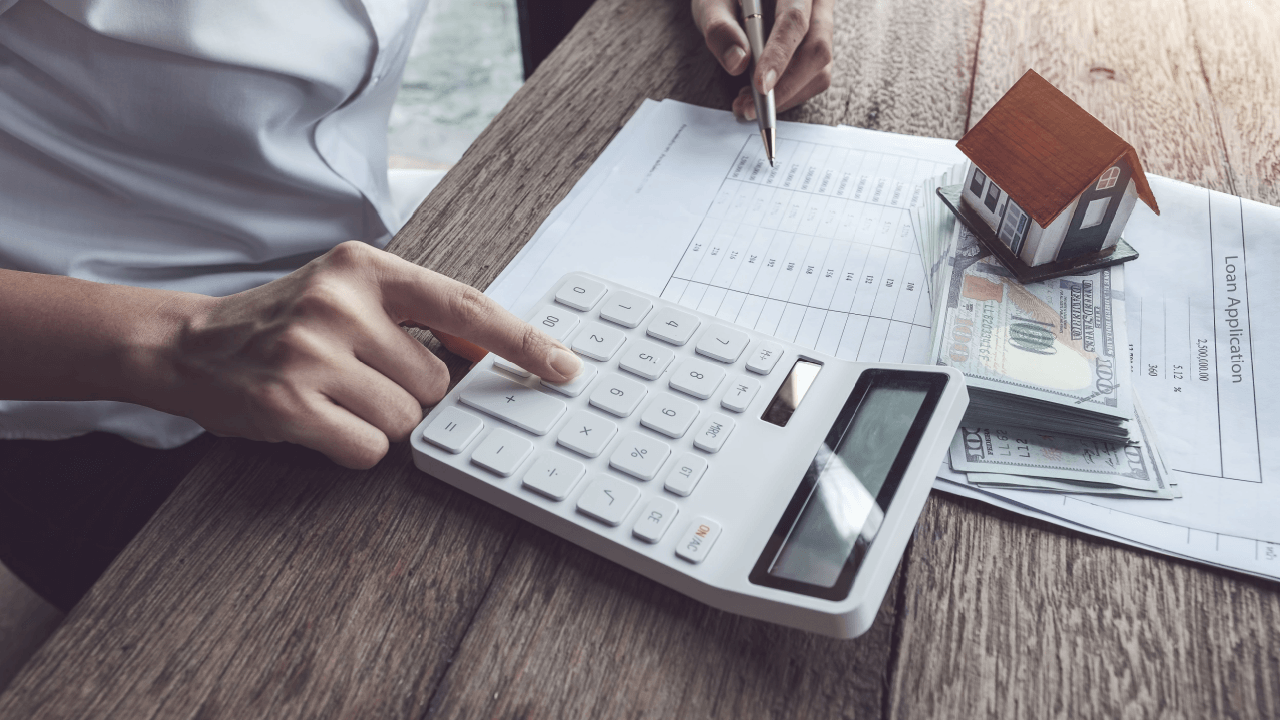 Person calculating how much does a criminal defense attorney cost with calculator, cash, and legal documents on desk