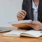 Professional criminal defense attorney reviewing legal documents at desk with laptop and scales of justice