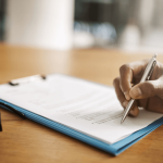 Person reviewing debt settlement documents with pen and clipboard asking is debt settlement ever a good idea