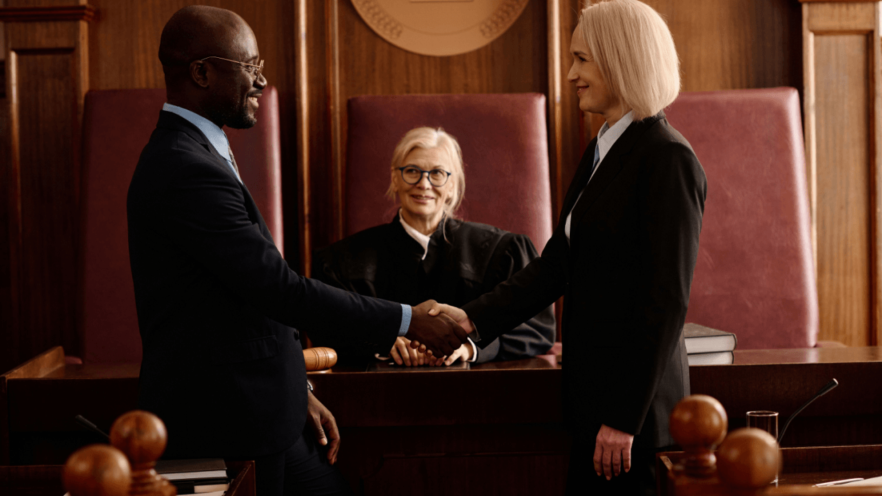 Two attorneys shaking hands in courtroom discussing is a defense attorney the same as a lawyer
