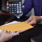 Two professionals discussing why do people settle instead of going to trial with documents and calculator on desk