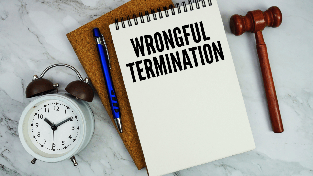 Wrongful termination notebook with gavel and clock on marble surface