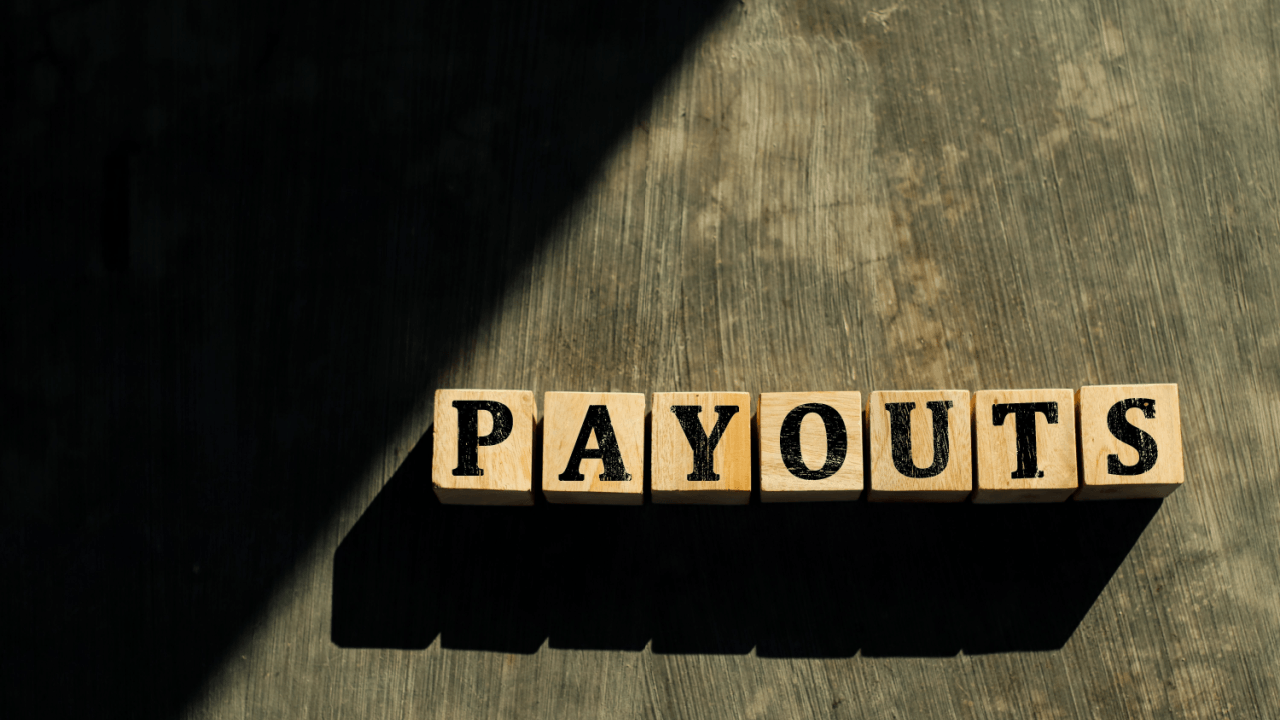 Wooden letter blocks spelling PAYOUTS on a rustic surface