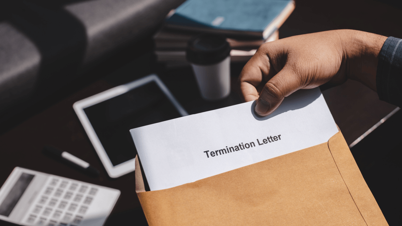 Person holding a termination letter in an envelope