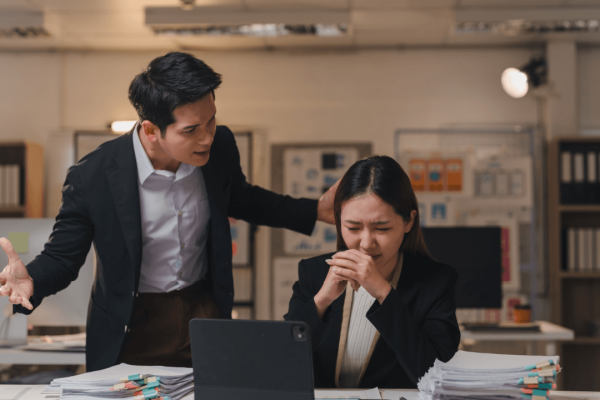 Distressed employee facing workplace intimidation depicting retaliation after reporting harassment