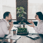 Two professionals having a serious conversation across an office desk