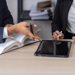 Attorneys reviewing legal documents and tablet to prove wrongful termination case