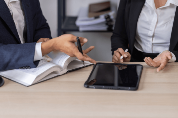 Attorneys reviewing legal documents and tablet to prove wrongful termination case