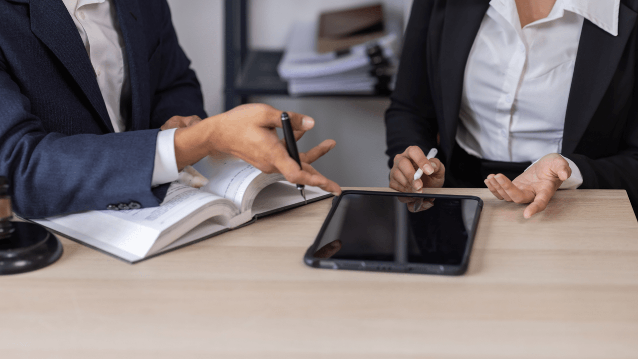 Attorneys reviewing legal documents and tablet to prove wrongful termination case