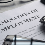Termination of employment letter on a desk with a watch, phone, glasses, and pen