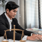 Lawyer researching gender discrimination in the workplace on laptop at desk with scales of justice