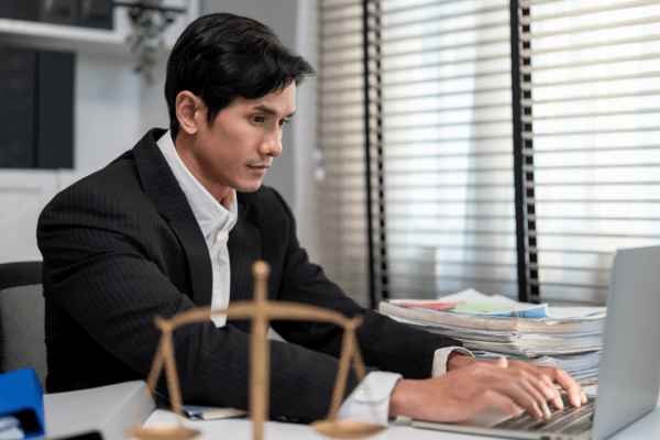 Lawyer researching gender discrimination in the workplace on laptop at desk with scales of justice