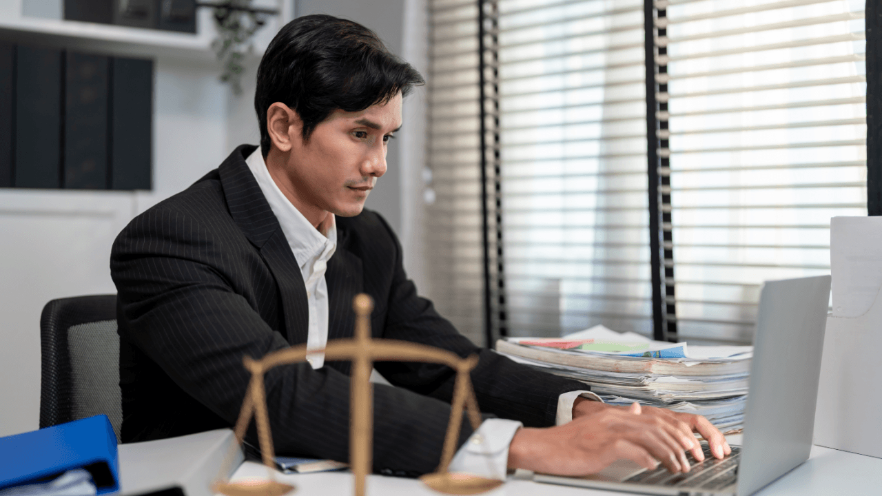Lawyer researching gender discrimination in the workplace on laptop at desk with scales of justice