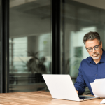 Workplace retaliation lawyer reviewing legal documents at office desk with laptop