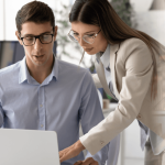 FMLA lawyer consulting with client at office desk reviewing case details on laptop
