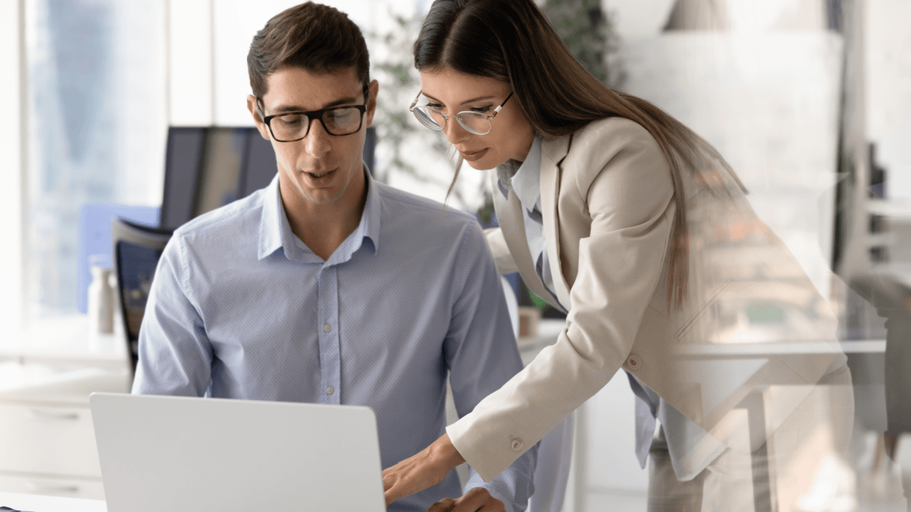 FMLA lawyer consulting with client at office desk reviewing case details on laptop