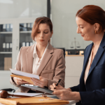 Two female attorneys reviewing documents on how to report workplace harassment in a law office