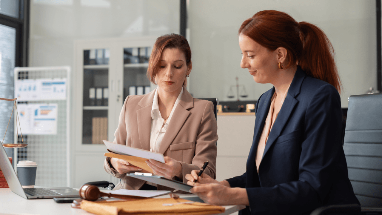 Two female attorneys reviewing documents on how to report workplace harassment in a law office