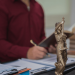 Personal injury lawyer reviewing case documents beside a scales of justice statue and gavel