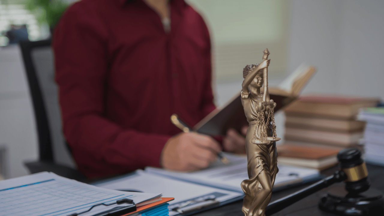 Personal injury lawyer reviewing case documents beside a scales of justice statue and gavel