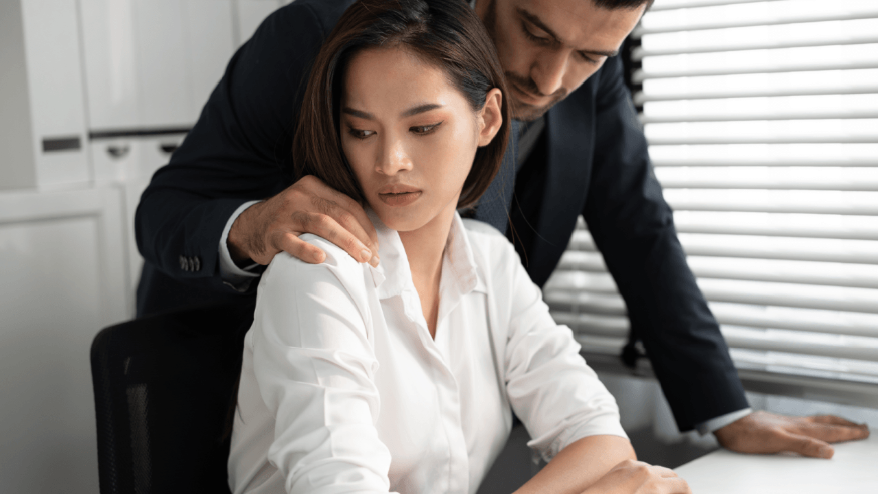 Woman experiencing sexual harassment at work rights violation by male coworker in office setting