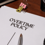 Overtime policy document on desk representing unpaid overtime employee rights in the workplace