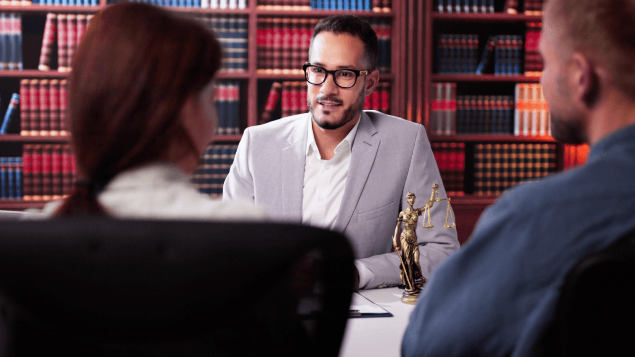 Attorney consulting with clients about whistleblower retaliation employee rights in law library