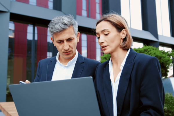 Workplace harassment lawyer consulting with colleague over laptop outside corporate building